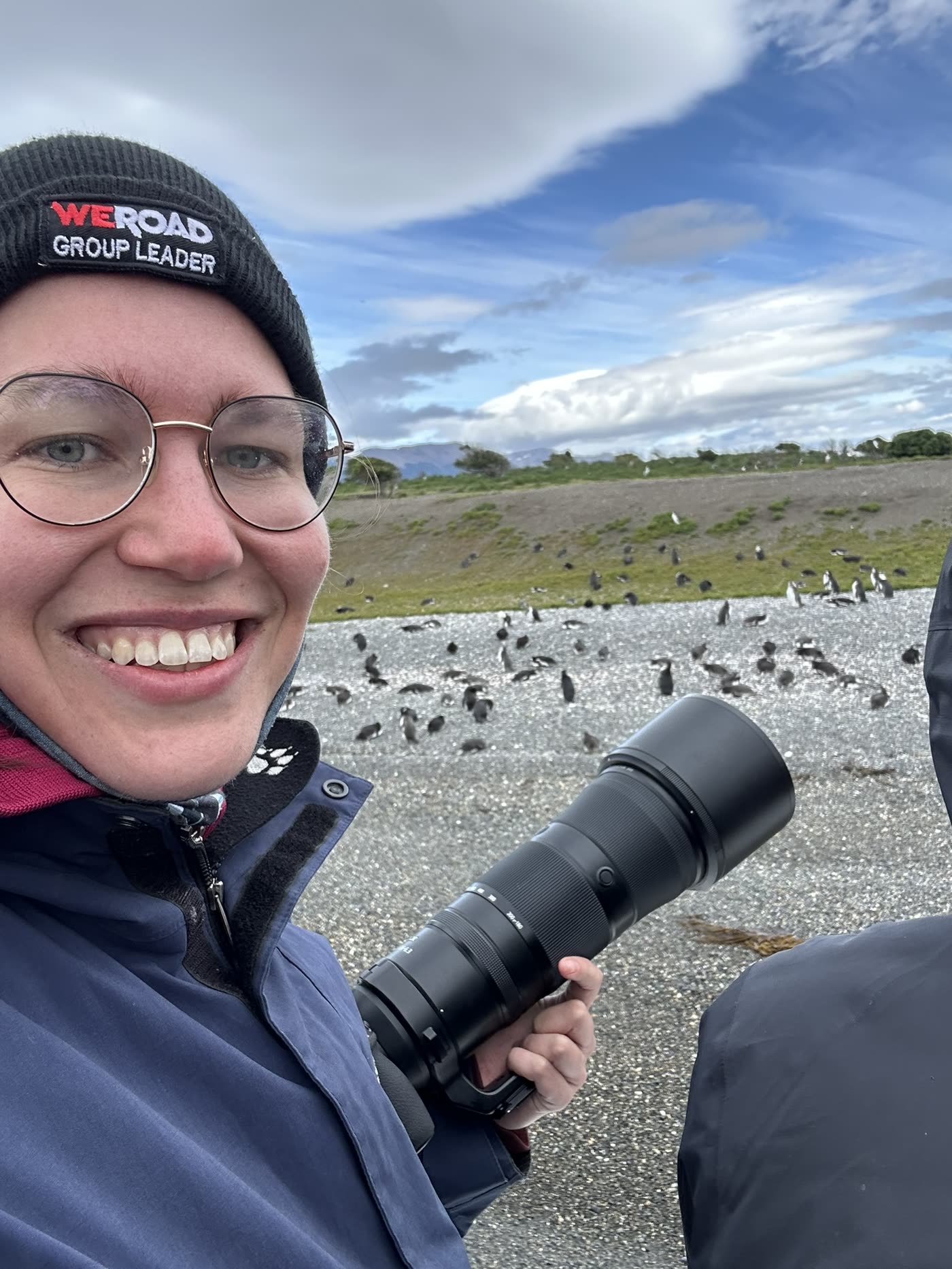 Janet mit Teleobjektiv vor einer Pinguinkolonie.