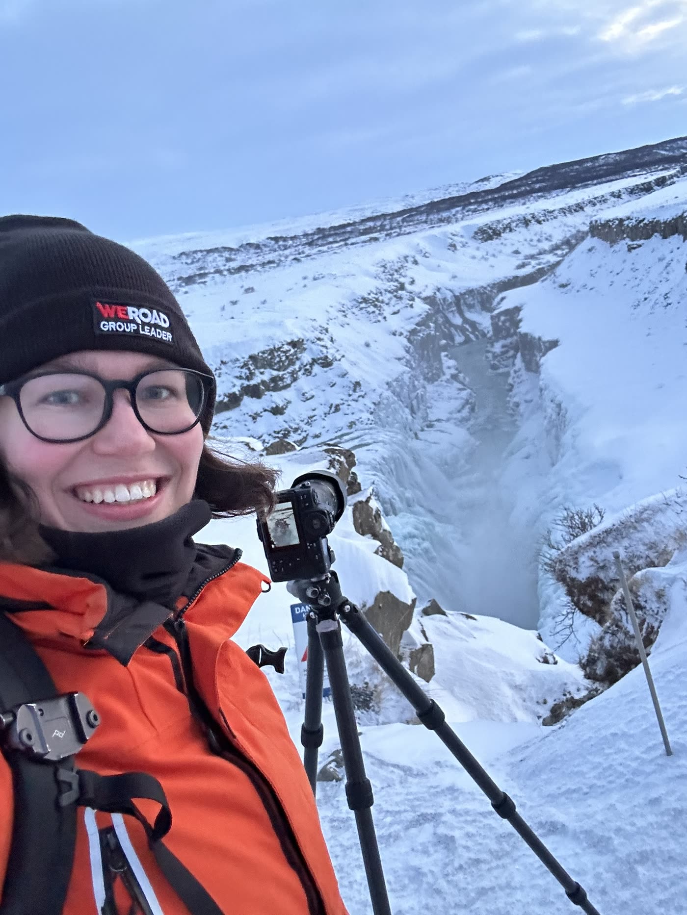 Janet mit Kamera und Stativ vor einer verschneiten Schlucht.