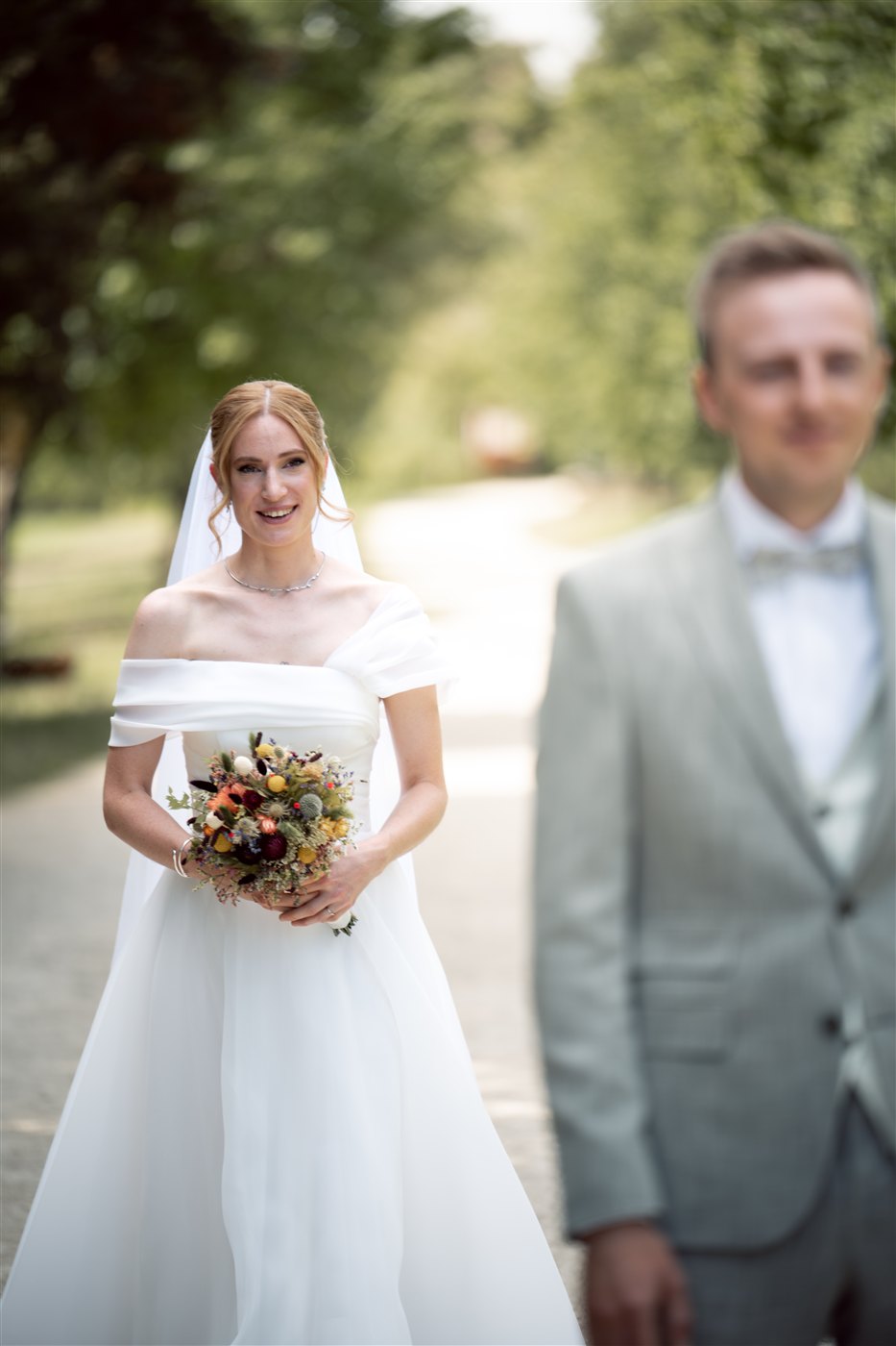 Eine Person mit Blumen nähert sich einer Person im grünen Anzug.