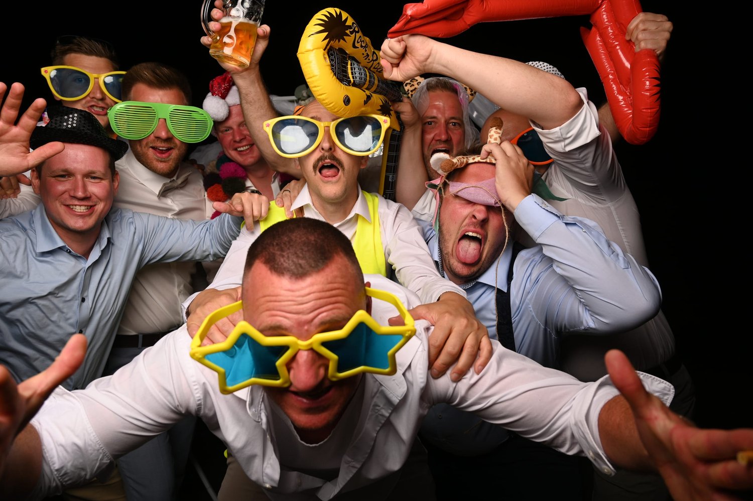Eine große Gruppe lacht mit Spaßbrillen in die Fotobox.