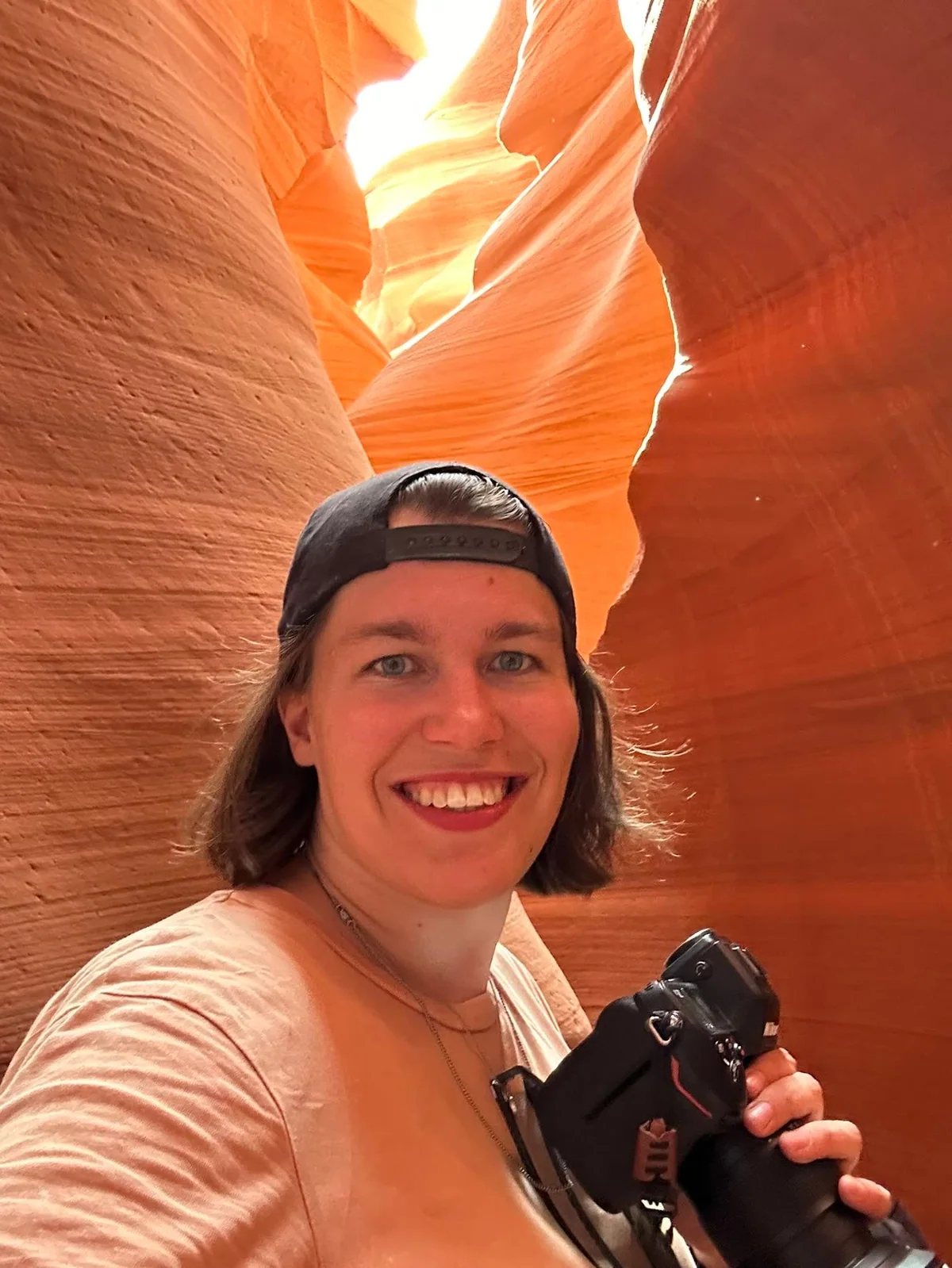 Janet with a camera in an orange glowing rock crevice.