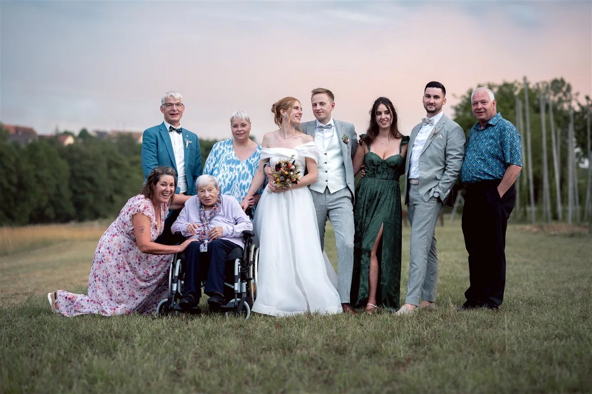 A family stand around the wedding couple at night, with one relative using a wheelchair.