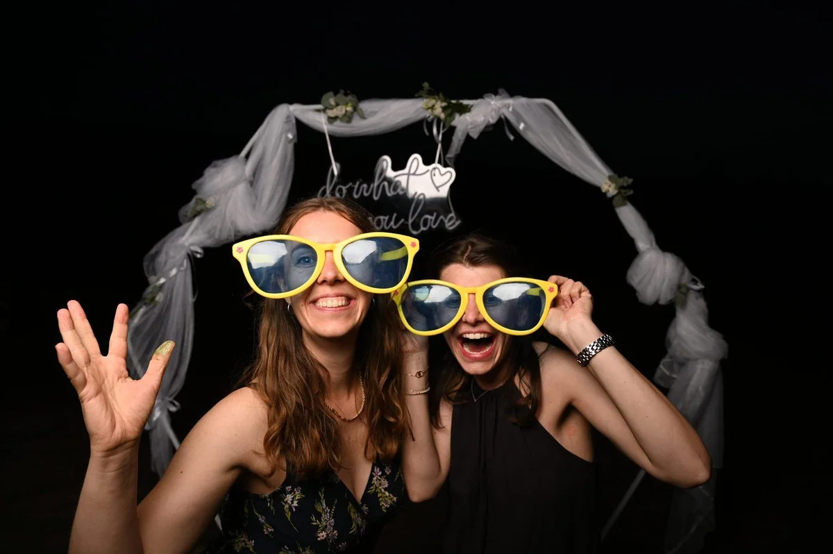 Two guests laugh in huge yellow sunglasses.