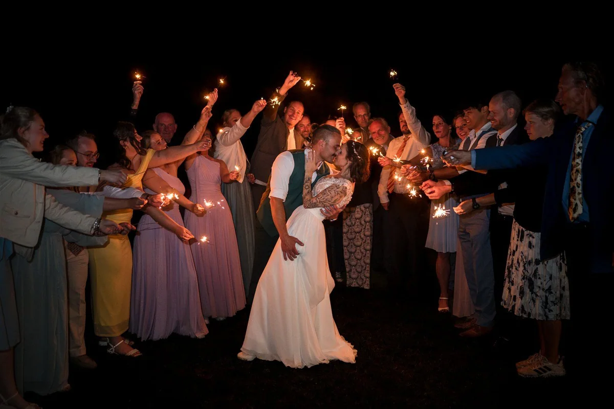 A bride walks between guests holding sparklers.