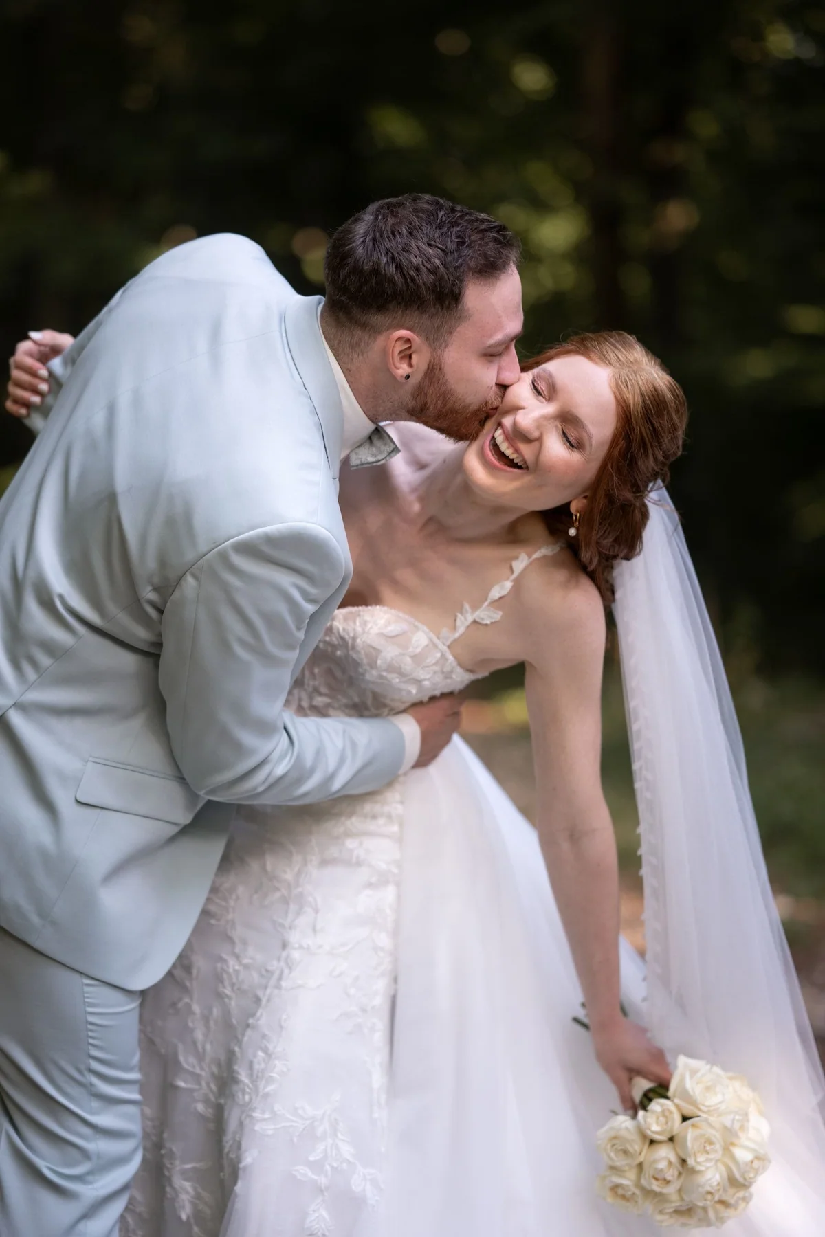 A bride laughs in her partner’s embrace.