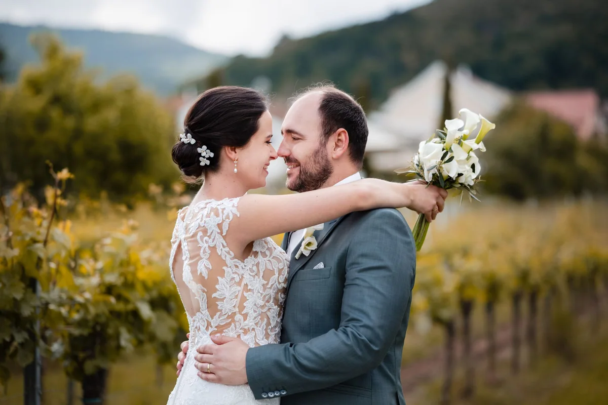 A wedding couple embrace laughing in the greenery.