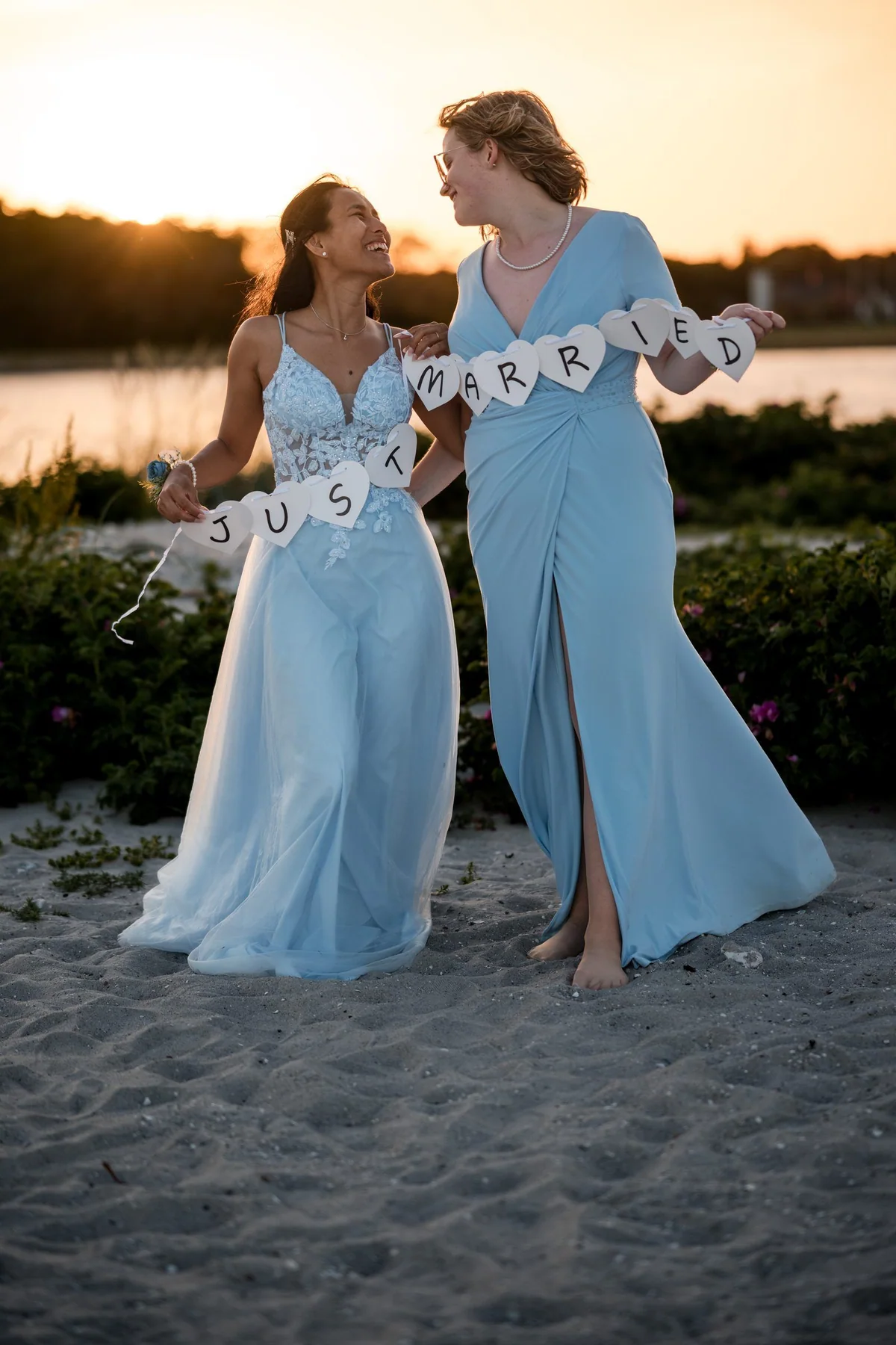 Die beiden halten am Strand eine Girlande mit der Aufschrift Just married.