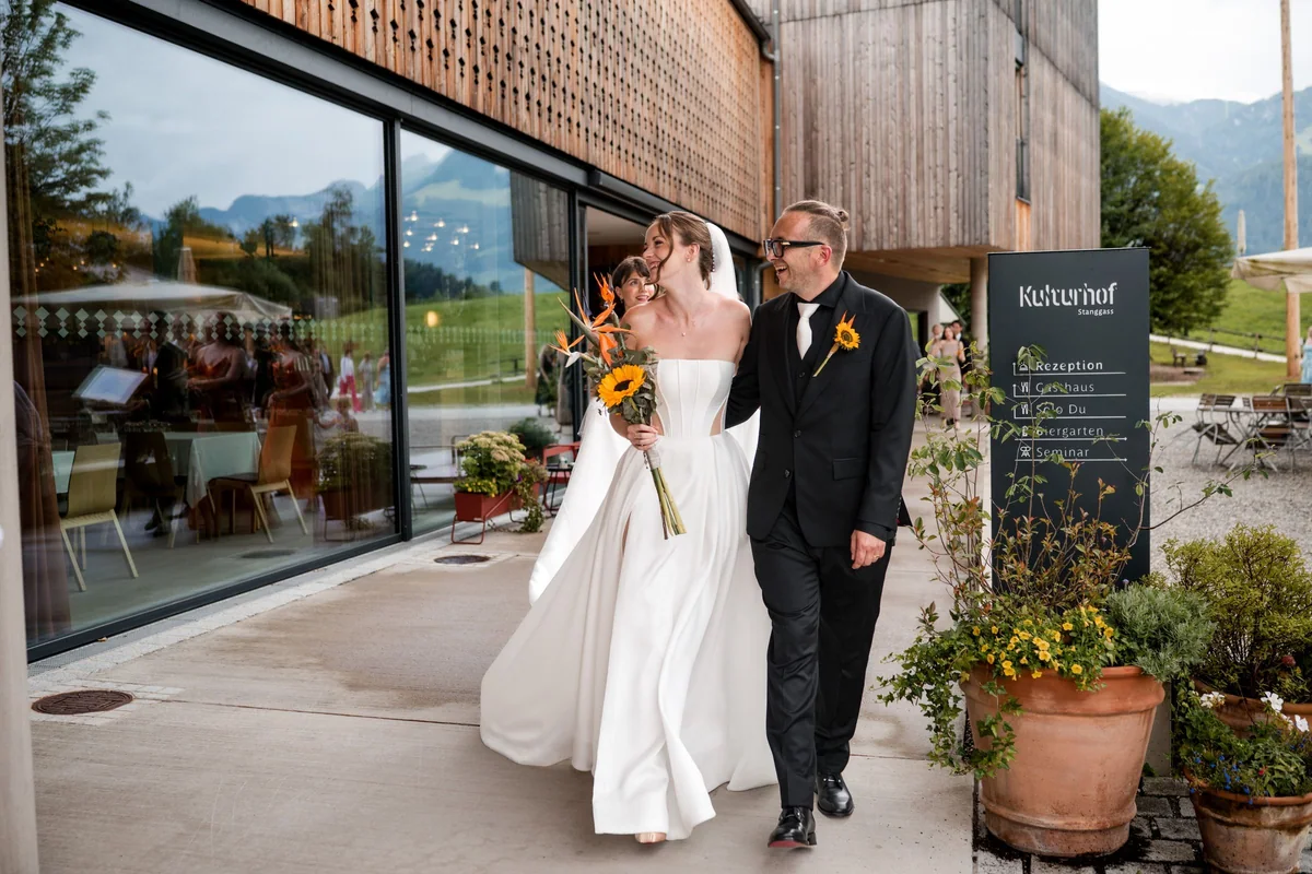 Brianna and her husband laugh in front of the glass facade of Kulturhof.