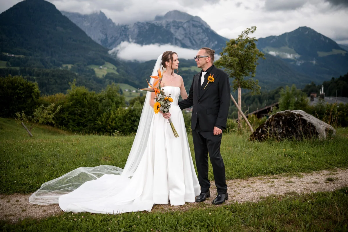 The wedding couple in front of cloud covered mountains.