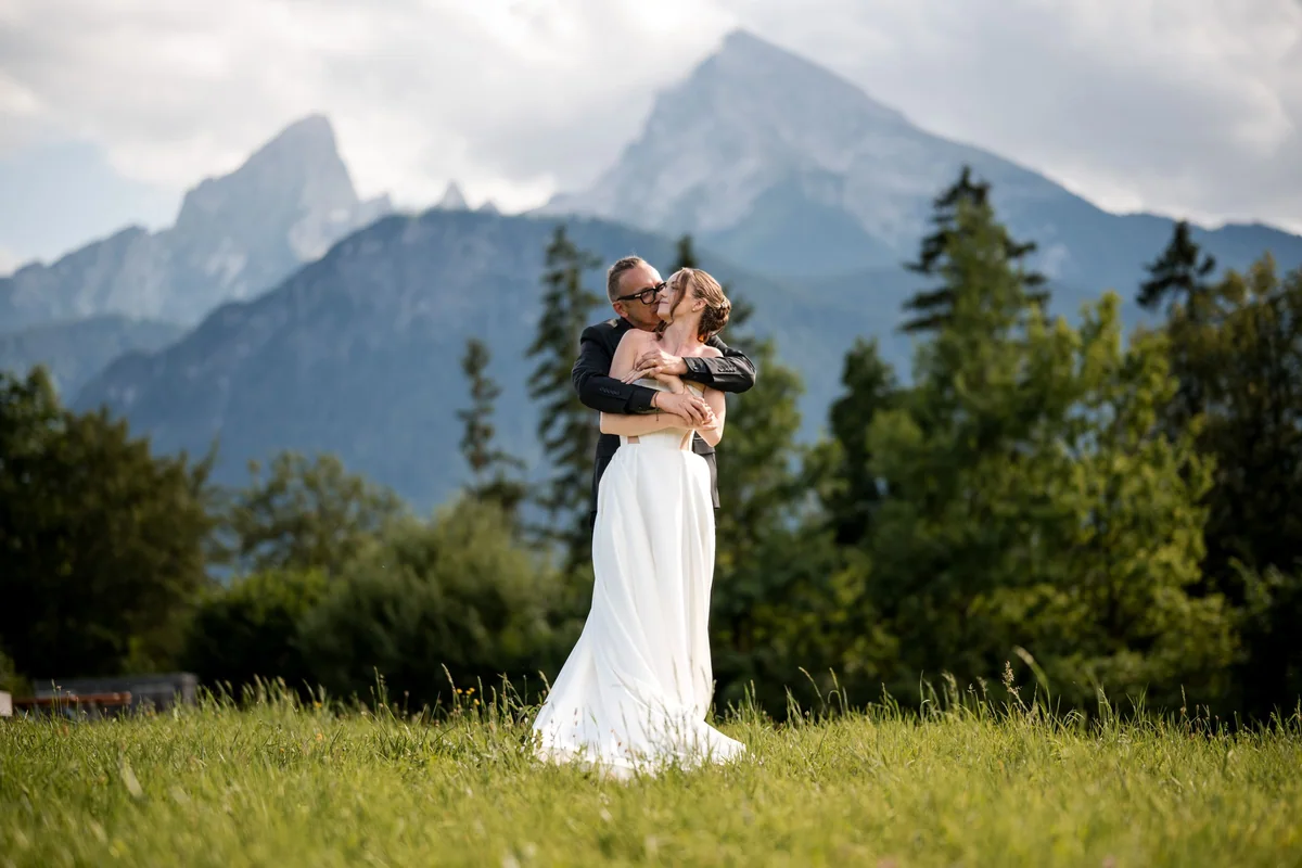 The wedding couple in a meadow in front of the Alps.
