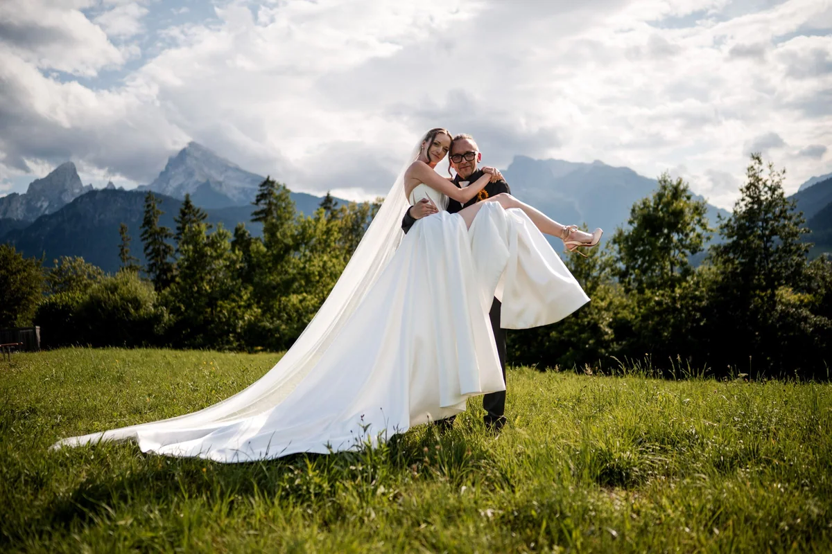 The groom carries Brianna in his arms.