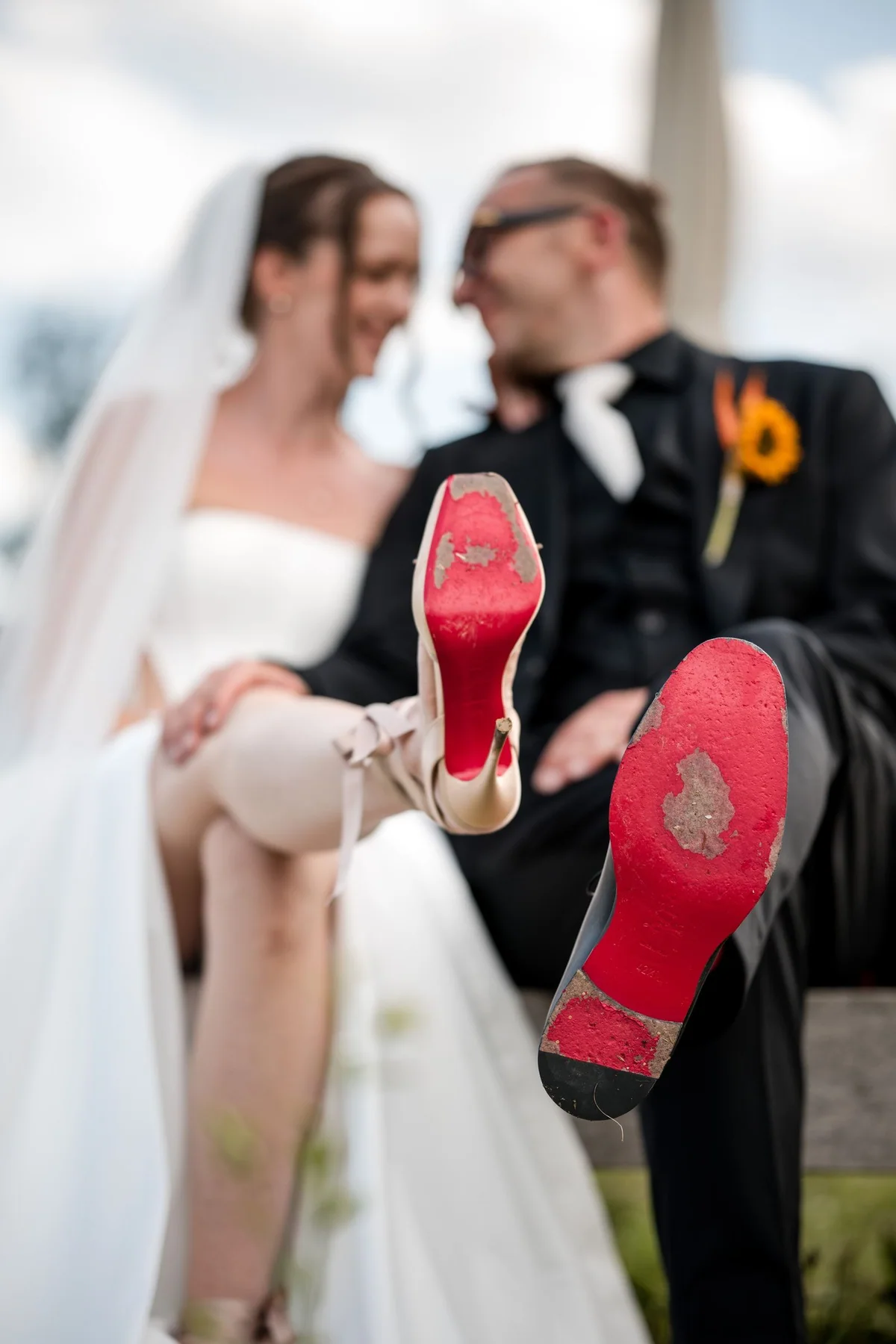 The seated wedding couple show the red soles of the bridal shoes.