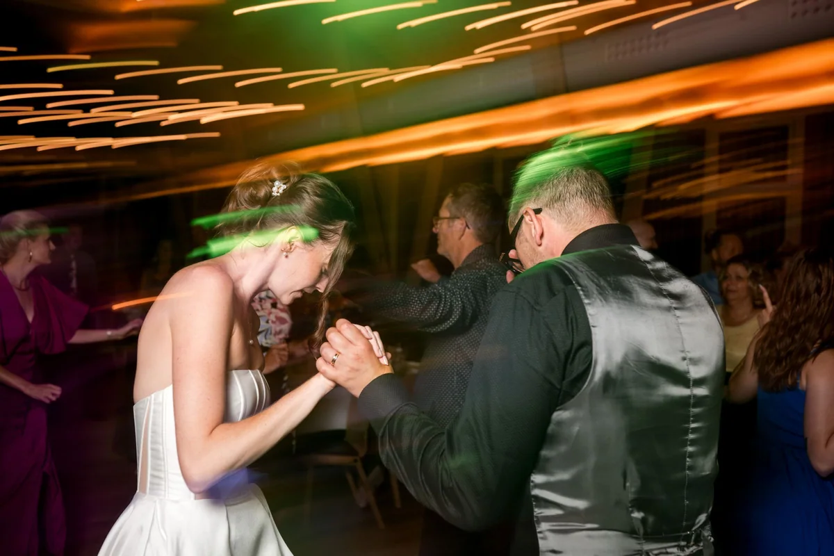 The wedding couple dance together among their guests.