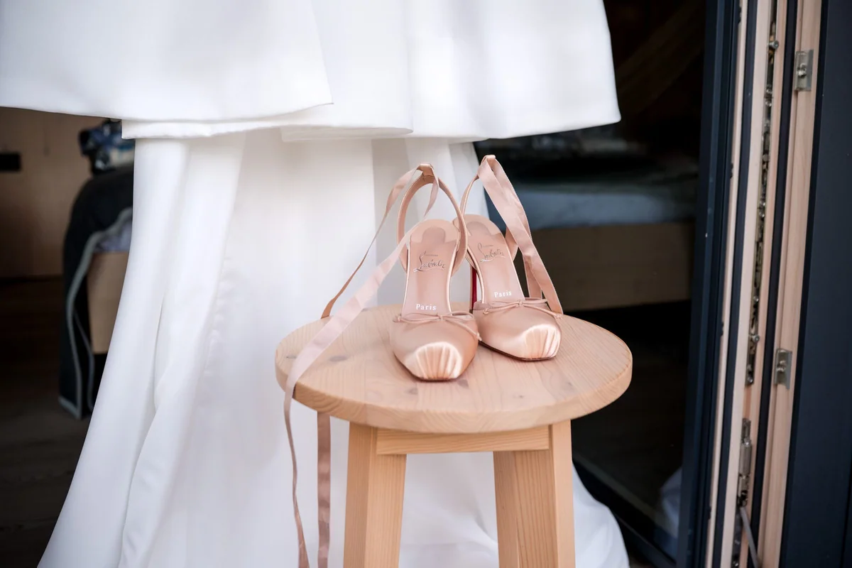 Bridal shoes beneath the hanging wedding dress.