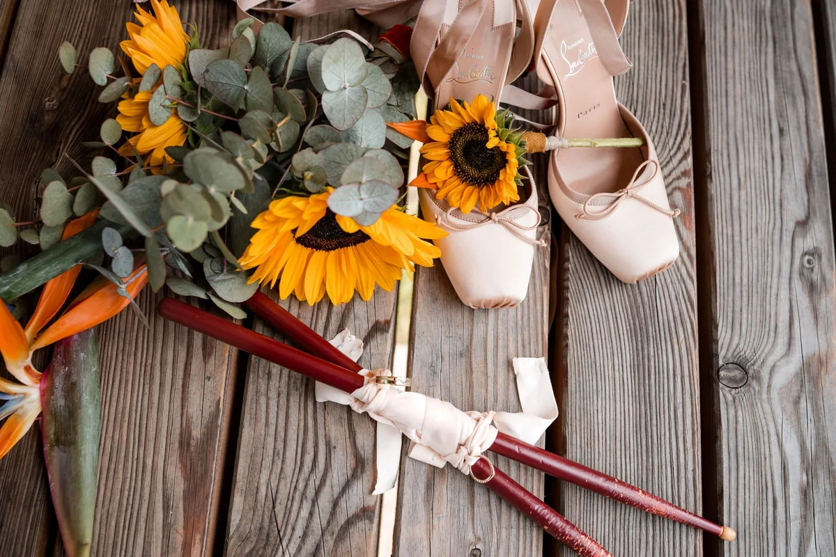 A sunflower bouquet and bridal shoes on wood.