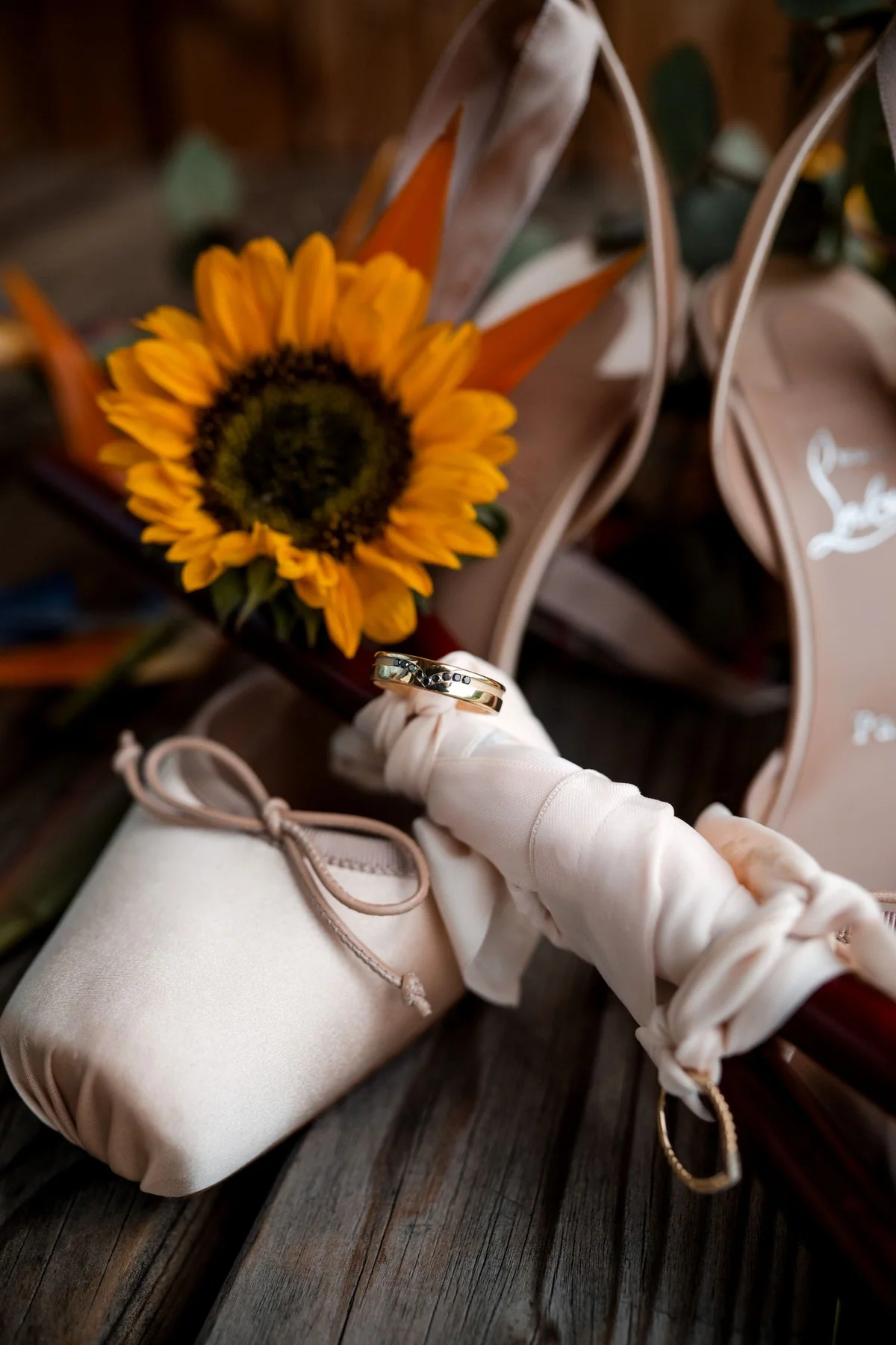 Bridal shoes beside a sunflower.