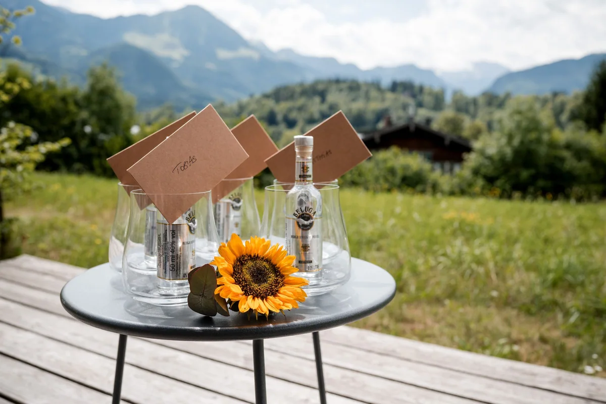 A sunflower, letters and drinks on a small table in front of the mountains.