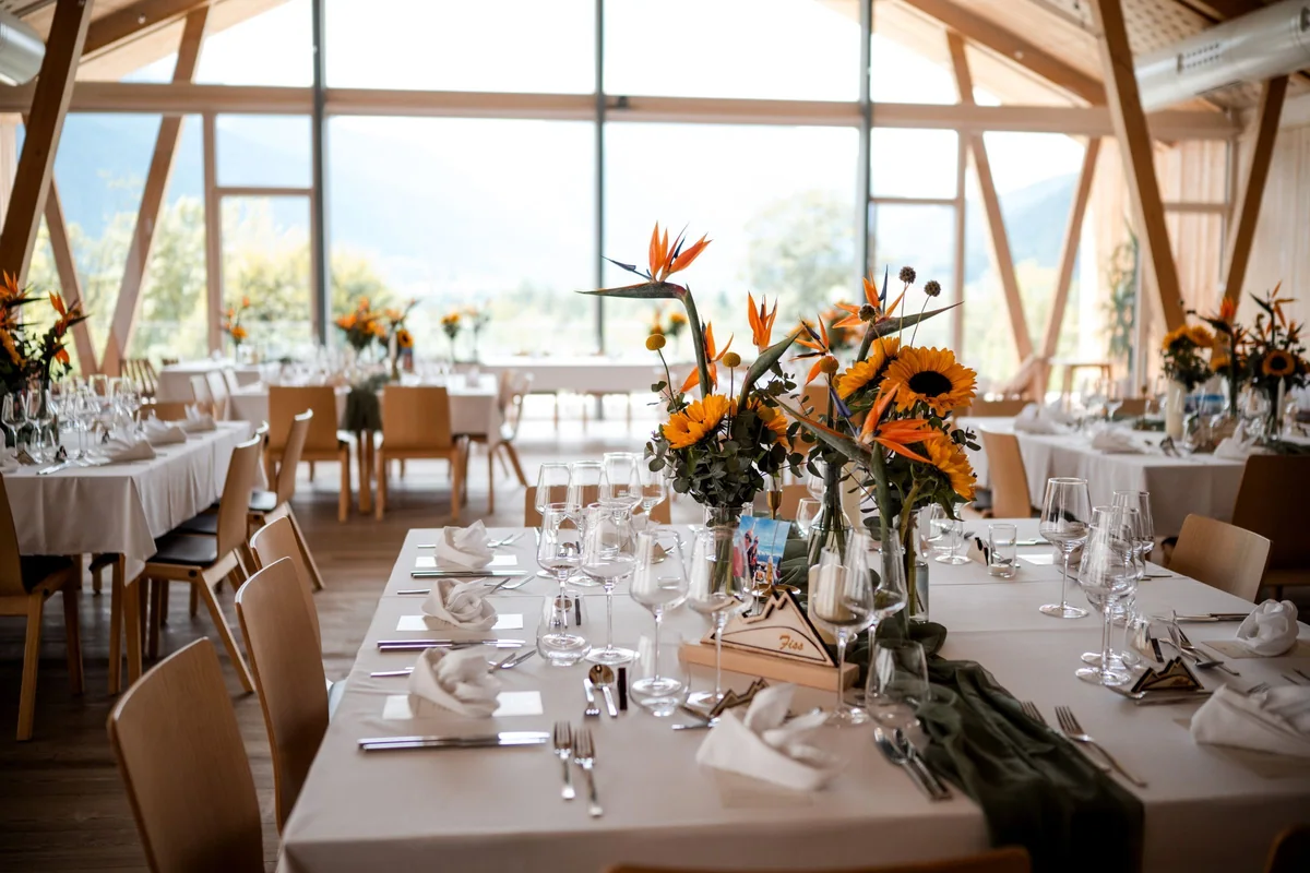 Tables set with sunflowers beside large windows at Kulturhof Stanggass.