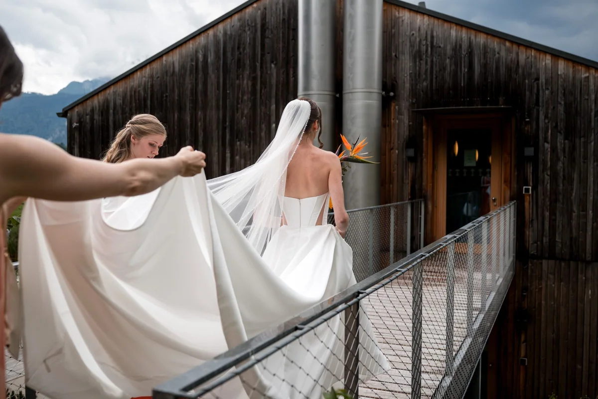 Brianna walks across the balcony while someone helps with her veil.