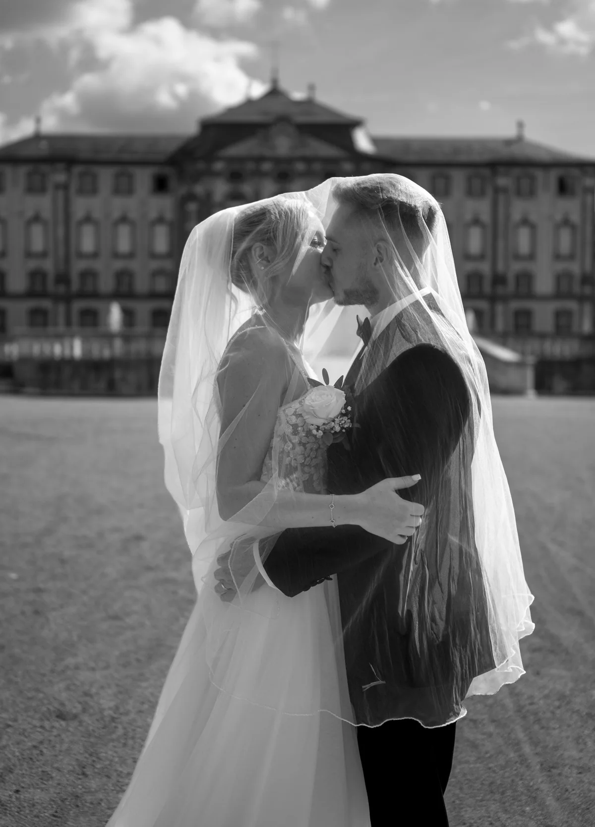 Black and white: the couple kiss beneath the veil, with Bruchsal Palace behind them.
