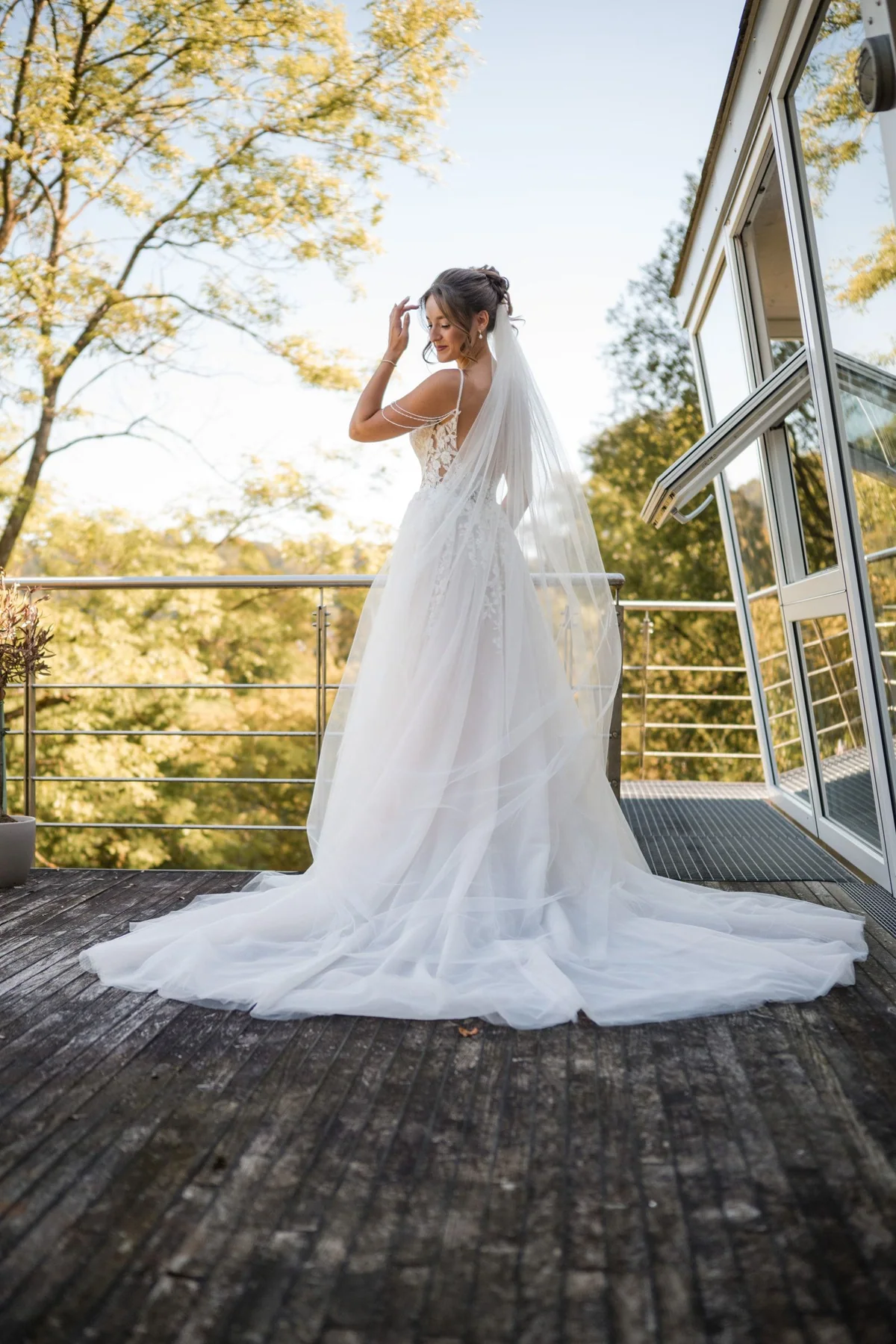 Die Braut steht im Kleid mit langer Schleppe auf einem Balkon.