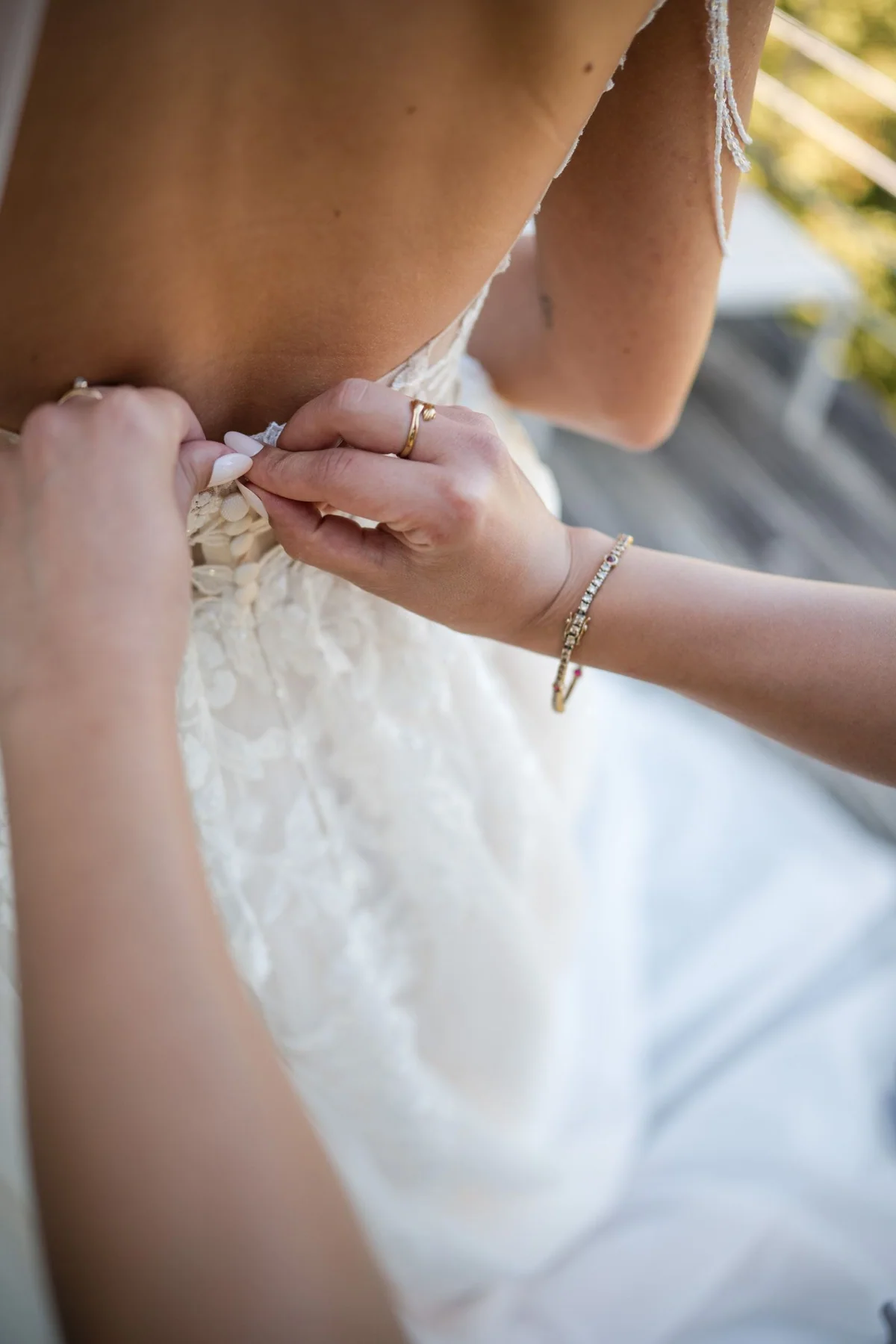 Eine Hand schließt das Hochzeitskleid am Rücken.