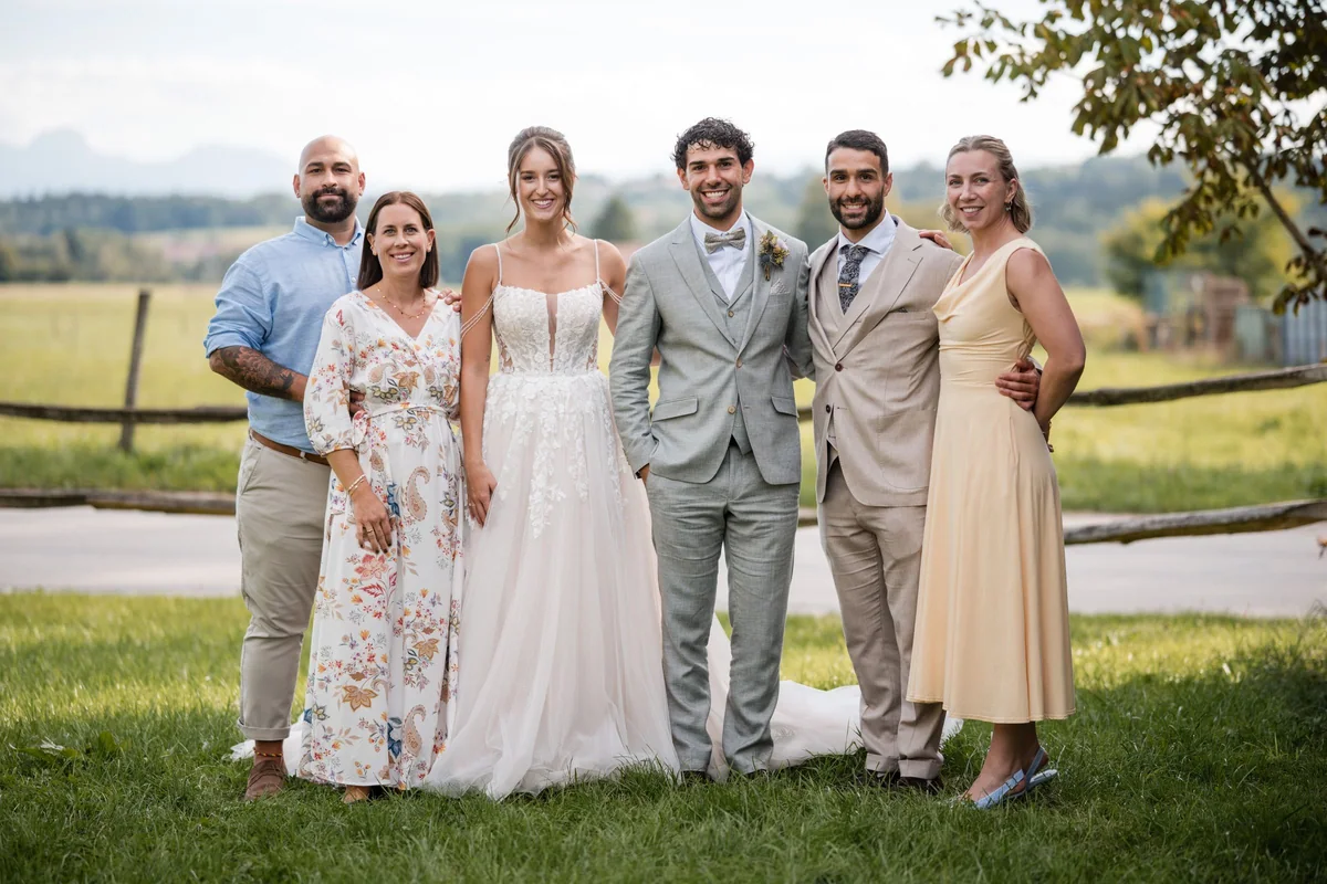 Leah und Sina stehen mit vier Gästen für ein Gruppenfoto auf einer Wiese.