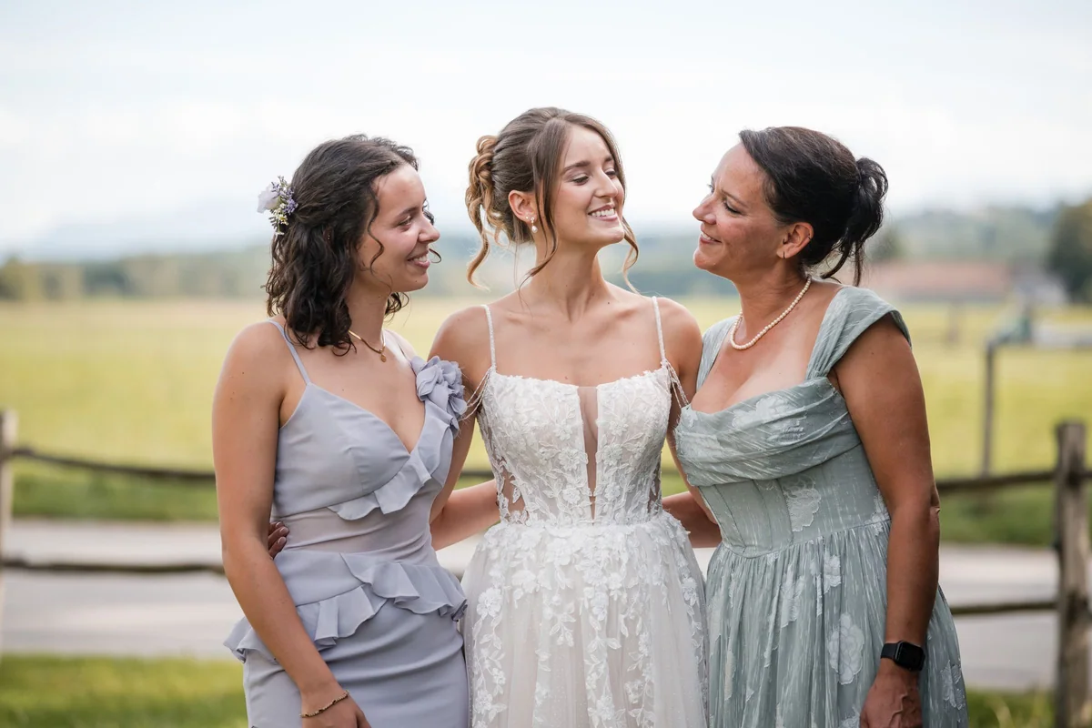 The bride laughs between two women leaning towards her.