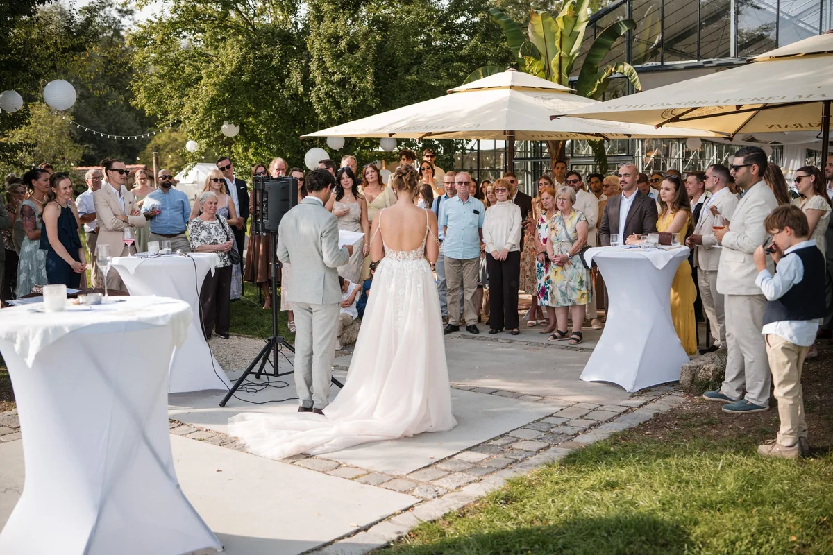 Die Braut steht vor der versammelten Hochzeitsgesellschaft auf der Terrasse.