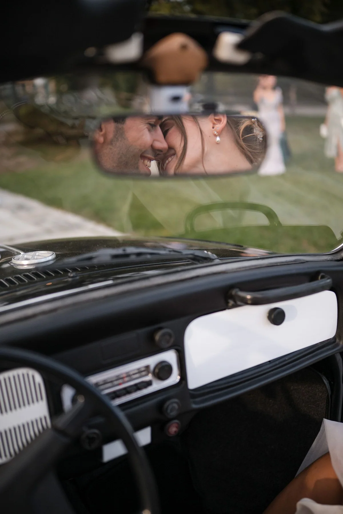 Das Paar ist zusammen im Rückspiegel des Oldtimers zu sehen.