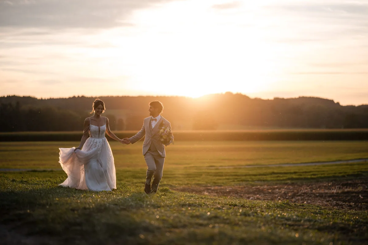 Leah und Sina gehen im Sonnenuntergang über die Wiese aufeinander zu.