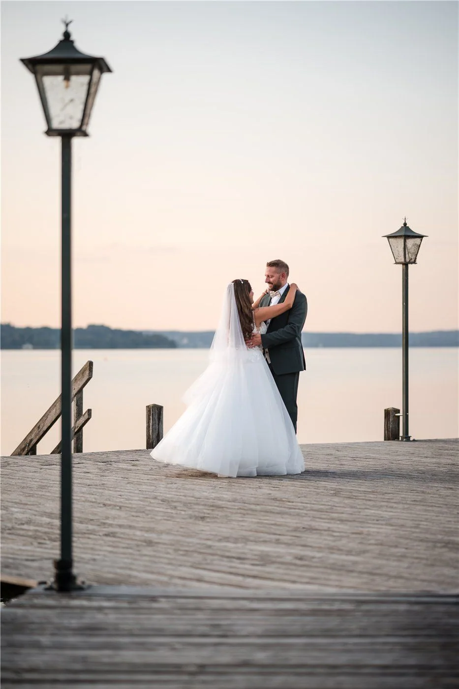 A wedding couple embrace among lanterns on the shore of Lake Starnberg.