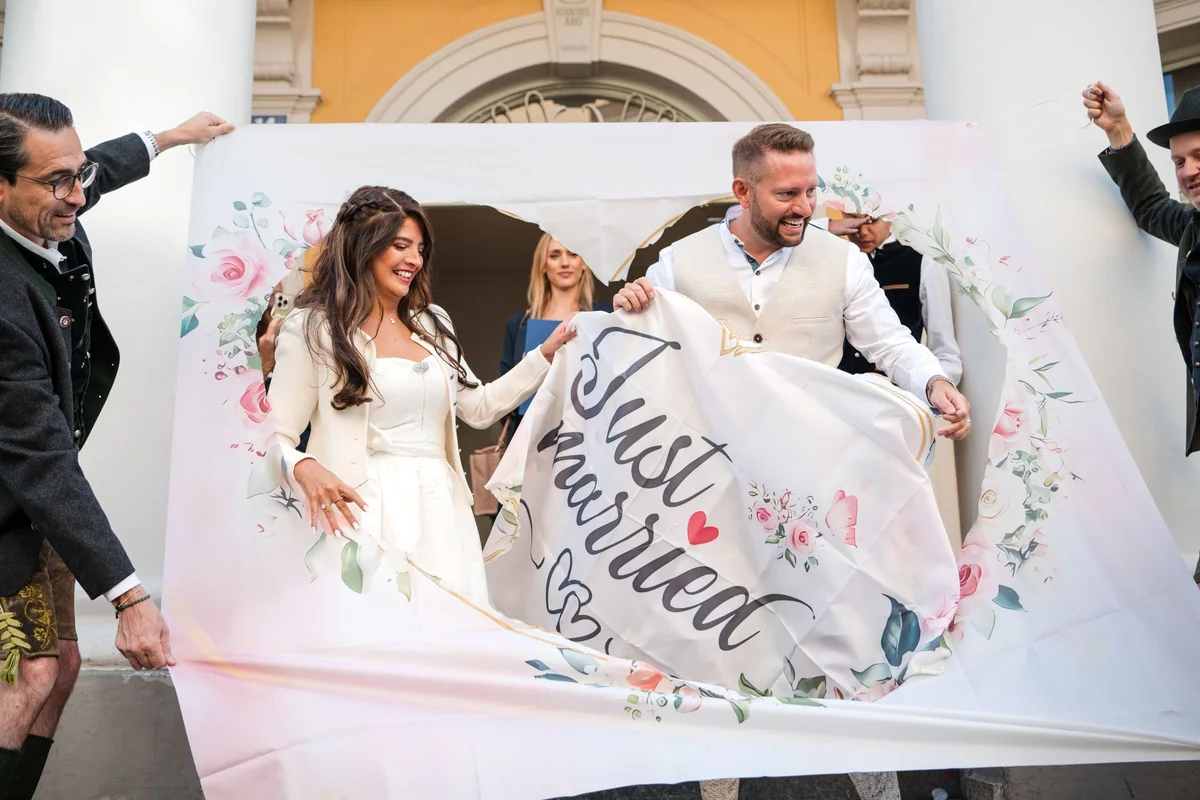 Das Paar schneidet sich durch ein Tuch mit der Aufschrift Just married.