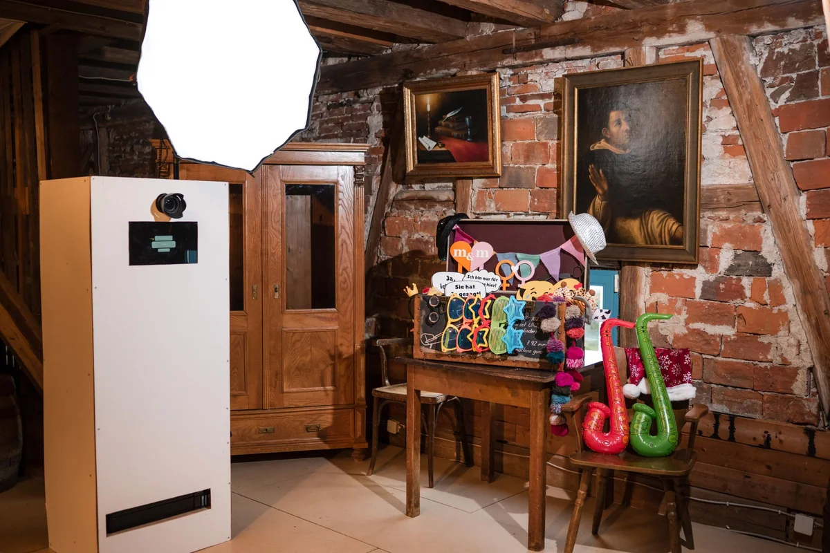 Die Fotobox mit Blitzschirm steht neben dem Tisch mit Props in der Scheune.