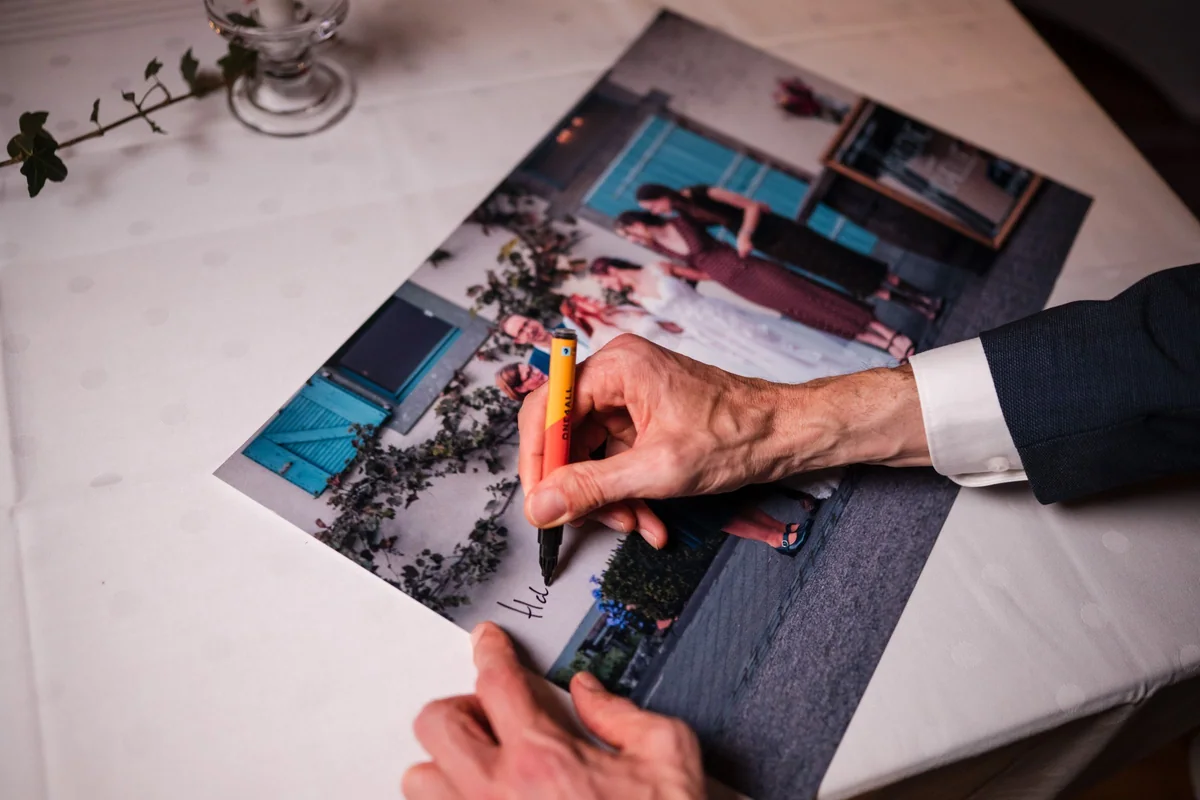 Ein Gast unterschreibt auf einem großen Ausdruck des Familienfotos.